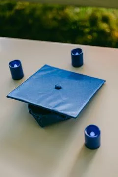 Graduation cap surrounded by candles displayed on a table in a serene outdoor Stock-Fotos
