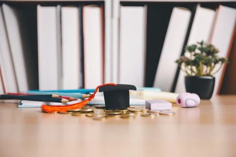 Graduation cap surrounded by coins, colored pencils, notebooks, eraser, and.. Stock Photos