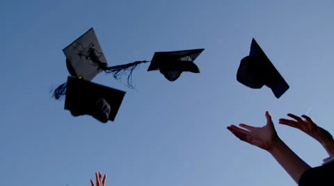 Graduation caps are tossed into the air on a bright sunny day Stock Footage