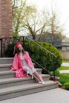 Graduation celebration with a student posing on steps wearing pink gown and.. Photos