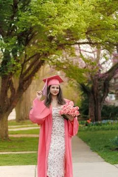Graduation ceremony taking place in spring with a student holding flowers o.. Stock Photos
