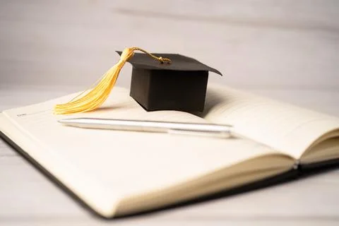 Graduation gap hat on open book; Education study testing learning teach con.. Stock Photos