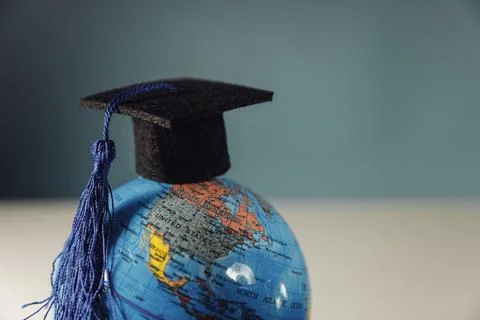 Graduation hat on globe model close-up. Education and scholarships concept Stock Photos