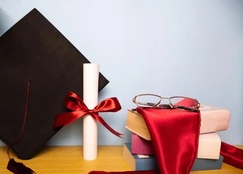 Graduation stole on stack of books diploma with red ribbon and graduation hat Stock Photos