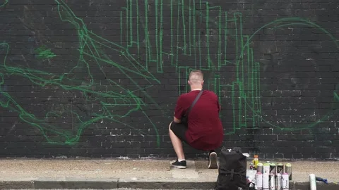 Graffiti artist making a sketch while people crossing in foreground Stock Footage 170728241