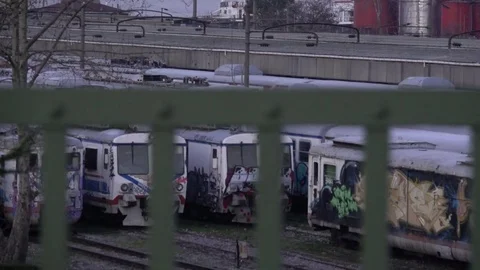 Graffiti trains viewed through fence Stock Footage 80950954