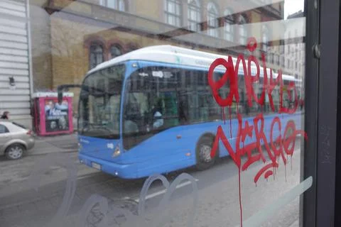 Graffiti on the window of the bus stop and a bus passing Stock Photos
