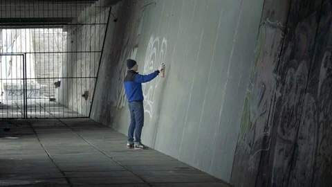 Graffiti. A young guy draws on the wall. Stock Footage 83160355