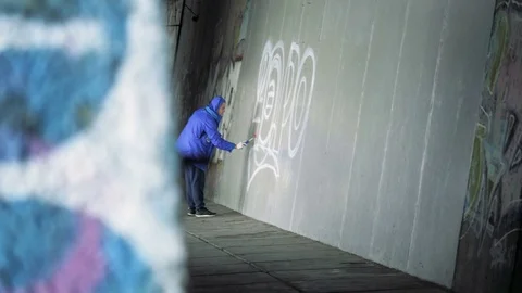 Graffiti. A young guy draws on the wall. Stock Footage 83160469