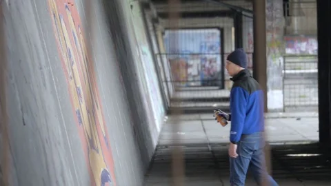 Graffiti. A young guy draws on the wall. Stock Footage 83160706