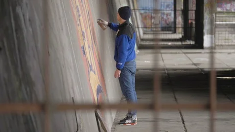 Graffiti. A young guy draws on the wall. Stock Footage 83160786