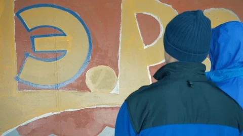 Graffiti. A young guy draws on the wall. Stock Footage 83160974