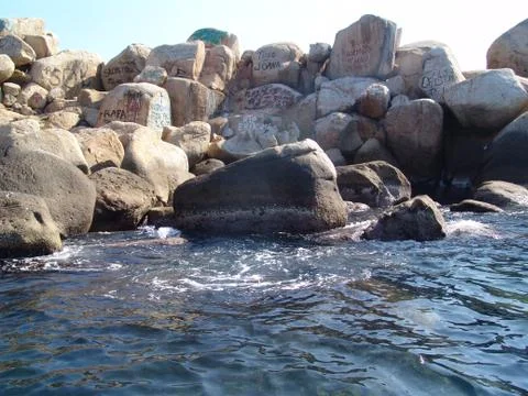 Graffitis on rocks in the ocean Stock Photos
