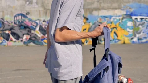 A graffitist puts on an open backpack full of paint cans. Stock Footage 81136407