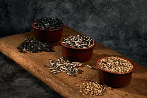Grain board. Two types of sunflower seeds and medicinal hemp seeds in ceramic Stock Photos
