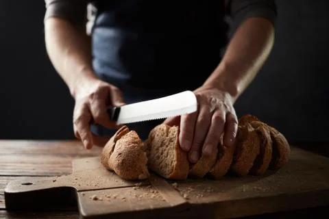 Grain bread put on kitchen wood plate with a chef holding knife for cut Stockfoto's