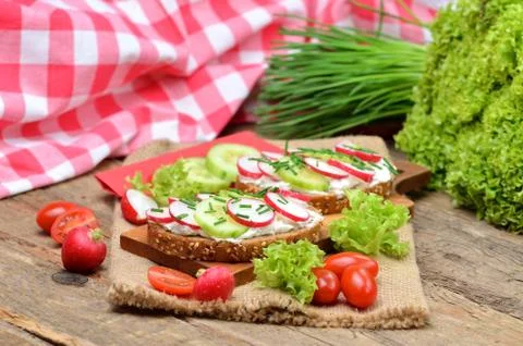 Grain bread with spread, fresh radish, cucumber and tomatoes on - concept of Stock Photos