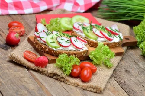 Grain bread with spread, fresh radish, cucumber and tomatoes on - concept of Stock Photos