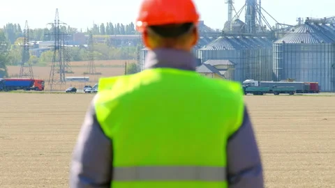 Grain elevator construction and worker walking in field Stock Footage 169102880