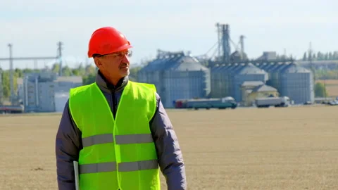 Grain elevator engineer walks looking at tablet in field Stock Footage 170443155