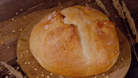 Grain falls on a loaf of white bread from above on a wooden background. Stock Footage 166682438