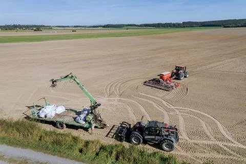 Grain loader and tractor with seeder in the field. Sowing grain using modern Stock Photos