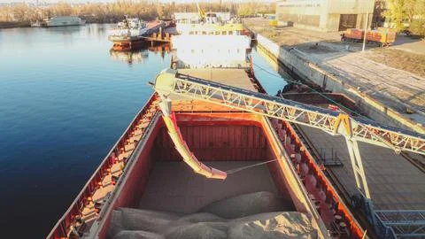 Grain loading in hold of bulk carrier ship with elevator crane closeup. Stock Photos