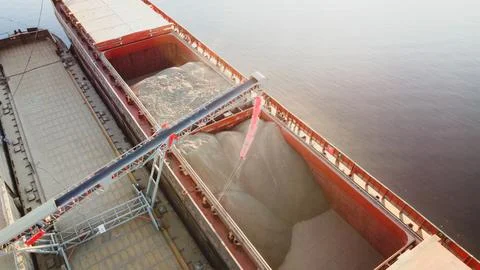 Grain loading in hold of bulk carrier ship with elevator crane closeup. Port Stock Photos