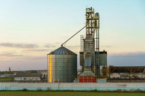 Grain silo elevator at sunset against the background of clouds. Iron barrels  Stock Photos