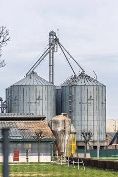 Grain Silos and Storage Facility Behind Harvested Field on Overcast Day in .. Stock Photos