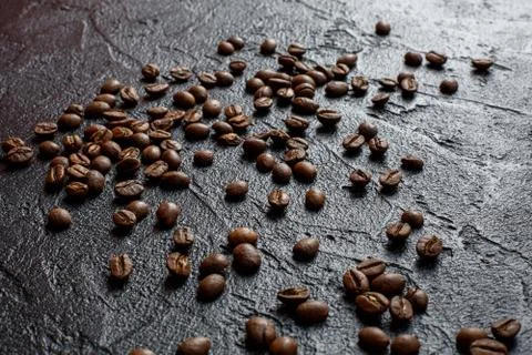 Grains of coffee are scattered on a black stone Stock Photos