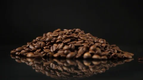 Grains of coffee on a black background. A soft light illuminates the grains. Stock Footage 98856397