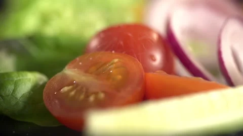 Grains of salt are falling on a vegetable salad of tomato, onion and lettuce Stock Footage