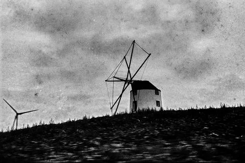 Grainy Windmill Silhouette Beneath a Clouded Sky Foto stock