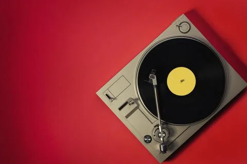 Gramophone with a vinyl record on a red table, top view and copy space,split  Fotos de archivo