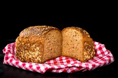 Granary spelt bread on red kitchen towel and black background Stock Photos