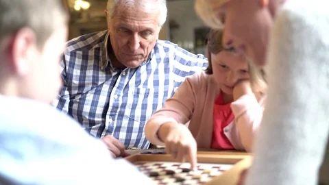 Grand-parents with grandkids playing checkers Stock Footage