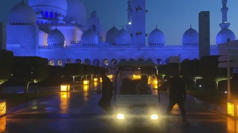 Grand Sheikh Zayed Mosque illuminated in striking blue light with golf cart Stock Footage 340255874