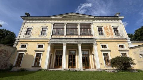 Grand weathered facade of an old classical yellow mansion with large windows Foto stock