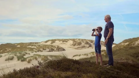 Grandchild on dune looking through binoculars Stock Footage 79143972