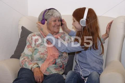Granddaughter And Grandmother Listening To Music Through Headphones Digital