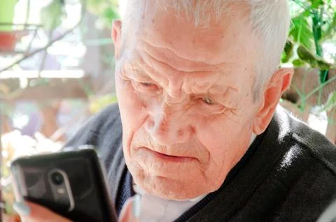 Granddaughter shows grandfather a photo of her grandson on the phone. The gir Stock Photos