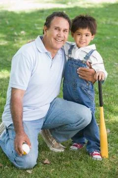 Grandfather and grandson holding baseball bat and smiling Stock Photos