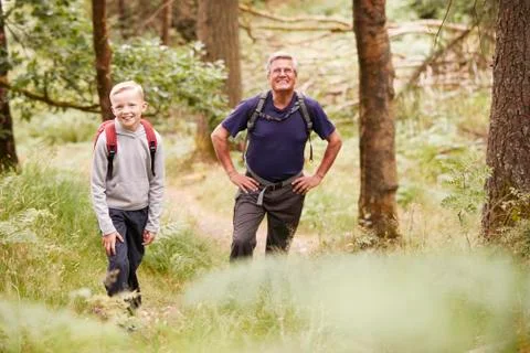 Grandfather and grandson taking a break while hiking in a forest, selective f Stock Photos
