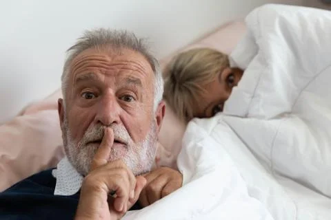 Grandfather ask to keep silence while grandmother is going to sleep Stock Photos