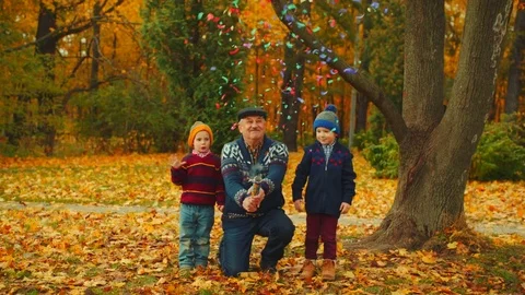 Grandfather is exploding party cracker in the autumn park with his grandsons Stock Footage 83742871