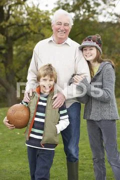 Grandfather with grandchildren holding football outside Stock Photos