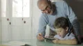 grandfather is learning from his grandson how to use a tablet to surf in web HD Footage