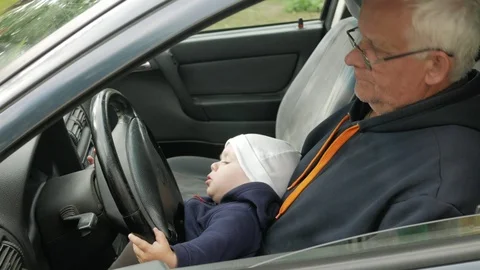 Grandfather plays with the boy in the car while driving. The grandson is very Stock Footage 76970979