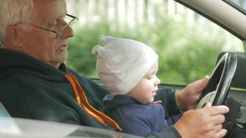 Grandfather plays with the boy in the car while driving. The grandson is very Stock Footage